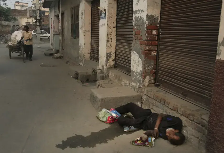 In this Oct. 31, 2019, photo, an Indian drug user lies unconscious by the side of a road in Kapurthala, in the northern Indian state of Punjab. Mass abuse of the opioid tramadol spans continents, from India to Africa to the Middle East, creating international havoc some experts blame on a loophole in narcotics regulation and a miscalculation of the drug’s danger. Punjab, the center of India's opioid epidemic, was among the latest to crack down on the tramadol trade. Researchers estimate about 4 million Indians use heroin or other opioids, and a quarter of them live in the Punjab, India's agricultural heartland bordering Pakistan. Image by Channi Anand / AP Photo. India, 2019.