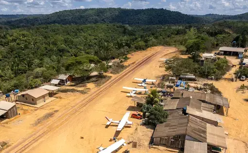 aerial shot of a dirt airstrip in a dense jungle