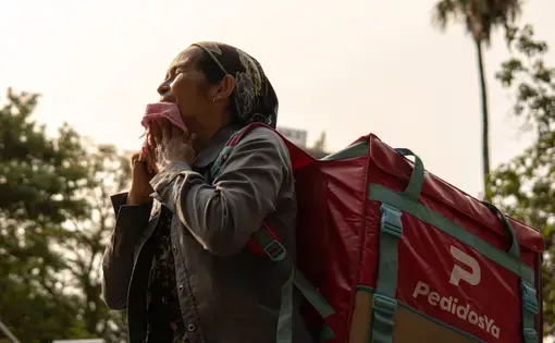 A woman carries a food delivery backpack in the heat