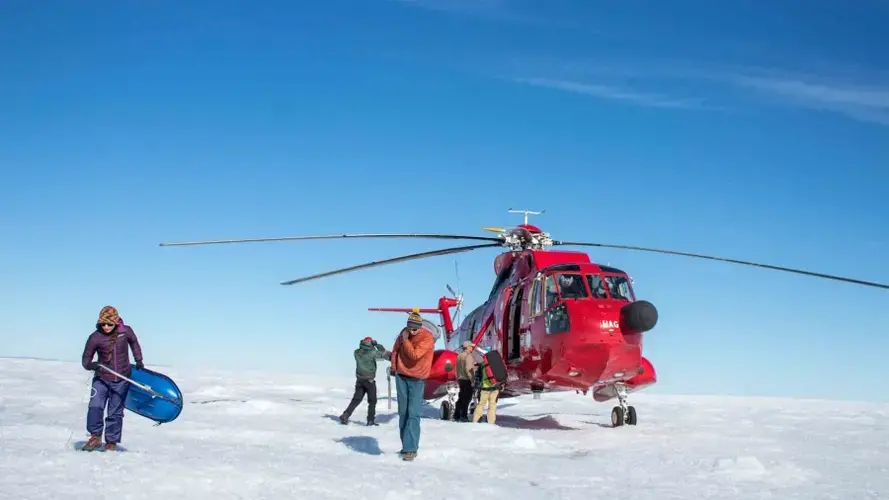 A team of three professors and three students unload a helicopter at their study site on the Greenland ice sheet. The team is studying ice sheet dynamics, or the ways the ice sheet moves slowly over the rock beneath it and into the sea. Image by Amy Martin. Greenland, 2018.