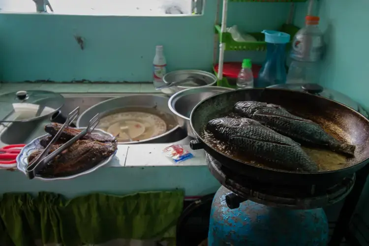 Quillo fries fish for lunch on a Sunday afternoon. She says they don’t have running water yet, so they rely on water they get from pumps outside their house to wash their dishes. Image by Micah Castelo. Philippines, 2019.