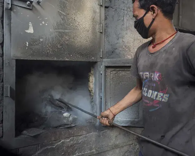 The Pollution Control Board has jurisdiction mainly over industrial units. In Bihar, that translates to thousands of tall chimneys that spew plumes of particles into the air. Here, an employee at a battery recycling facility feeds a smelter. Image by Larry C. Price. India, 2018.