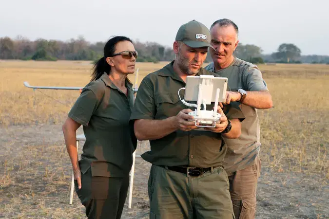 Antoinette Dudley, Stephan De Necker, center, and Otto Werdmuller Von Elgg piloting a drone and viewing its footage live. Such drones could help keep elephants away from park fences, to reduce conflicts with villagers living nearby. Image by Rachel Nuwer. Malawi, 2016.