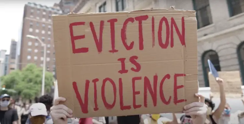 A protester holds a sign reading, "Eviction is violence"