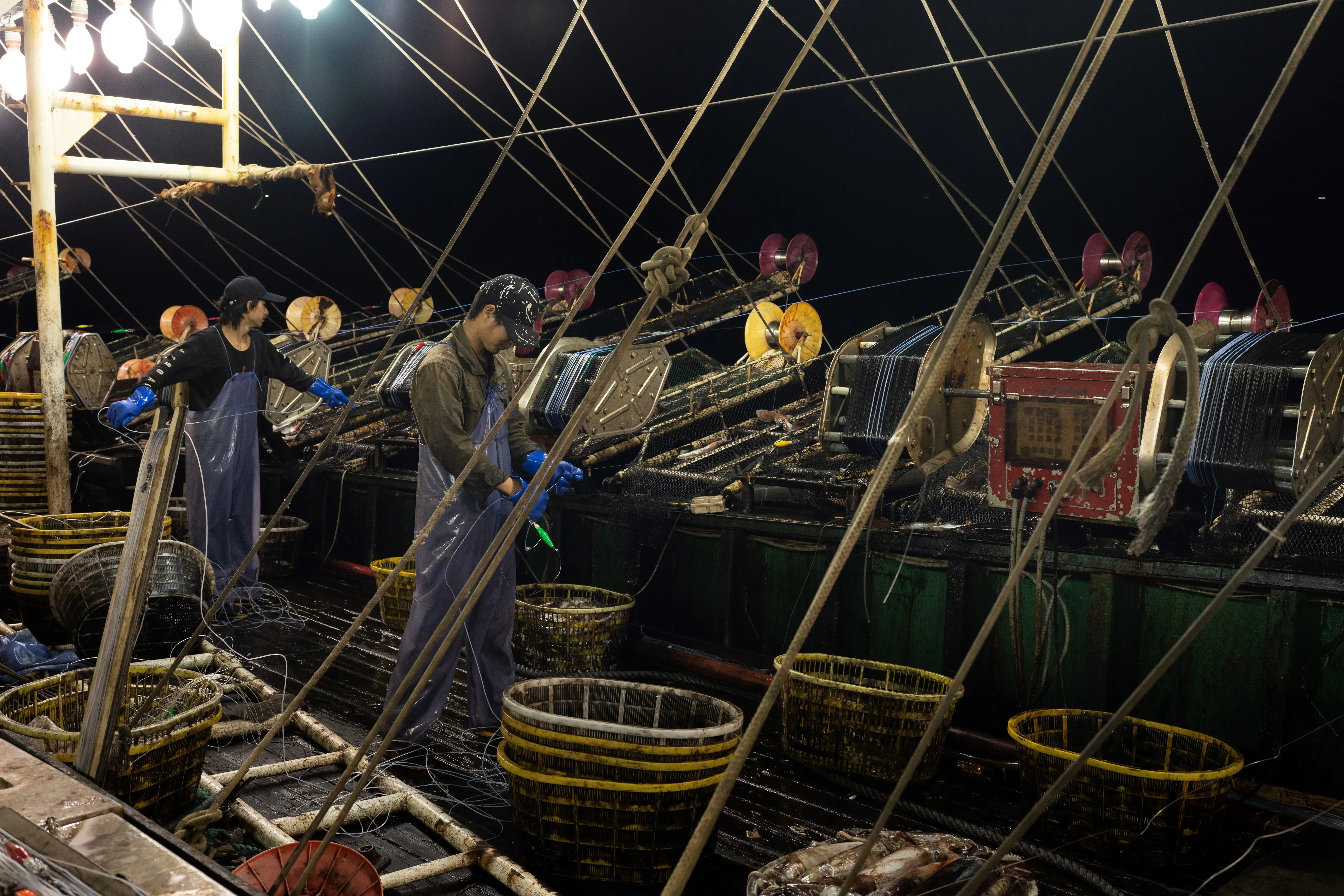 The crew aboard a Chinese fishing vessel use jigs and bright lights to catch squid at night on July 7, 2022. Image by Ed Ou/The Outlaw Ocean Project.