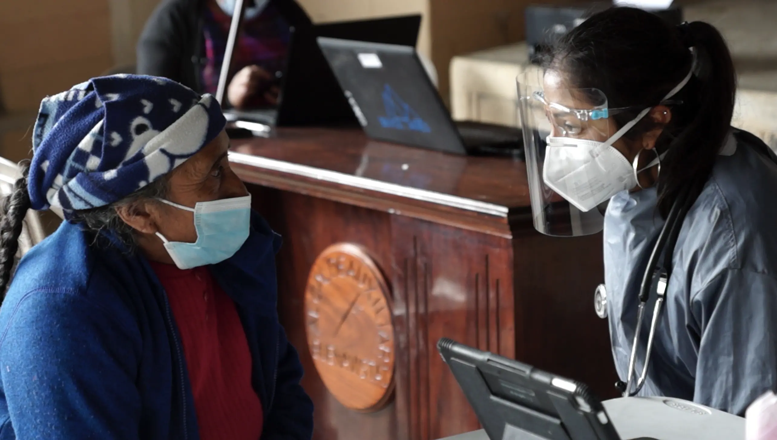 Woman consults patient from behind face shield
