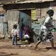 A woman with child on her back carries a wash basin in the Kawangware slum in Nairobi, Kenya. Image by Mark Hoffman. Kenya, 2017. 
