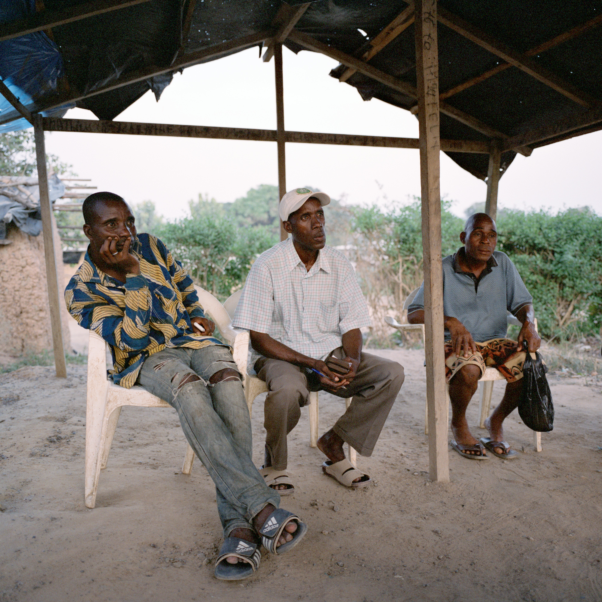 Beugré Djié, Kofi Raymond Wodoh, and Lucien Tagnon, from left, in Moussadougou, Ivory Coast. Moussadougou is a farming community that has rapidly grown to 30,000 people over the past few decades, most of them "immigrants" from northern Ivory Coast. The three men pictured here are from the local Bakwé ethnic group. Their minority status and support for former president Laurent Gbagbo, coupled with claims that as the local tribe they should be given rights to land, have caused tensions. Image by Peter DiCampo. Ivory Coast, 2012. Media file: -3.jpg