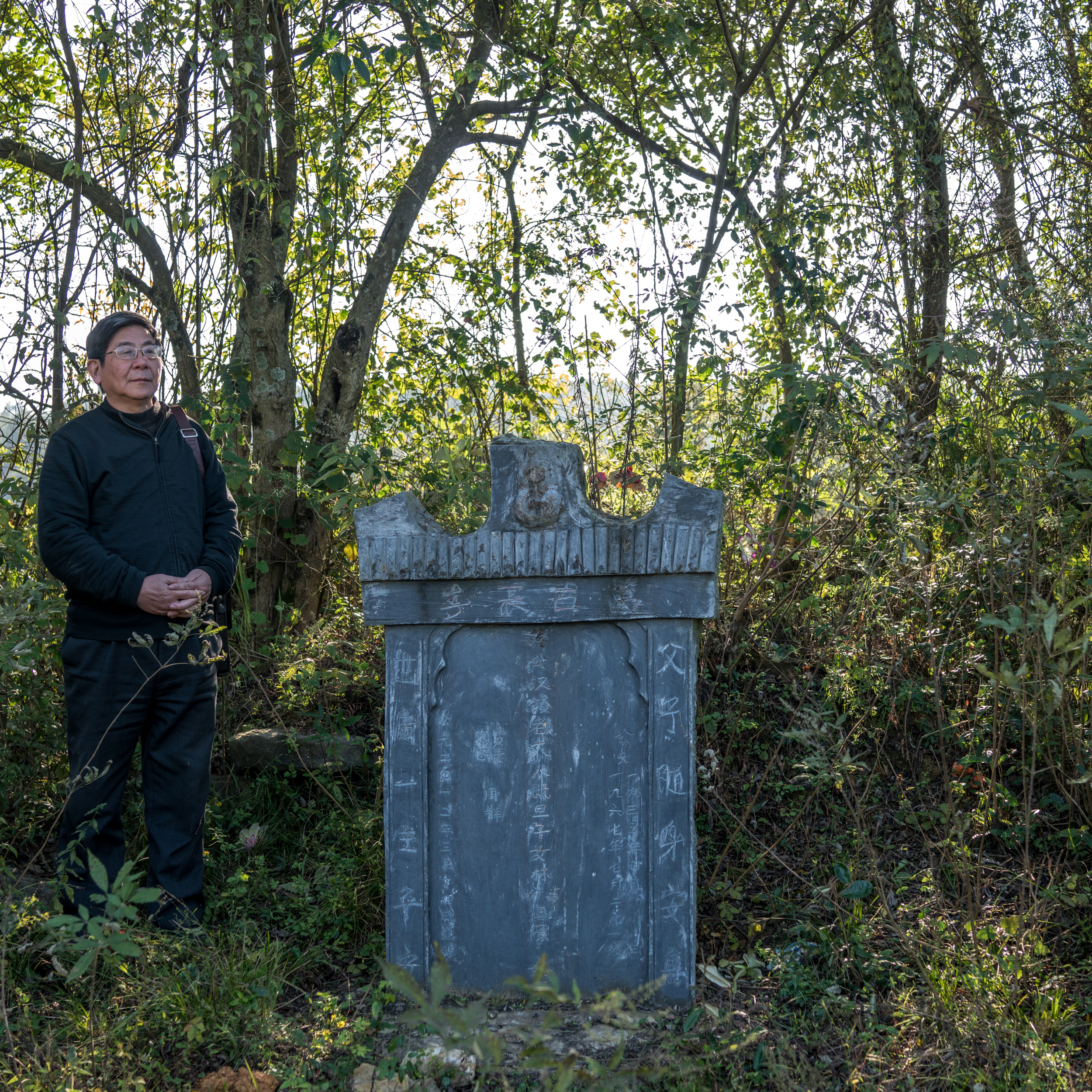 Tan Hecheng at a tombstone put up by Zhou Qun for her husband and three children, who were among the thousands of people killed during the Cultural Revolution in Dao County. Image by Sim Chi Yin. China/VII, 2016. Tan Hecheng at a tombstone put up by Zhou Qun for her husband and three children, who were among the thousands of people killed during the Cultural Revolution in Dao County. Image by Sim Chi Yin. China/VII, 2016.