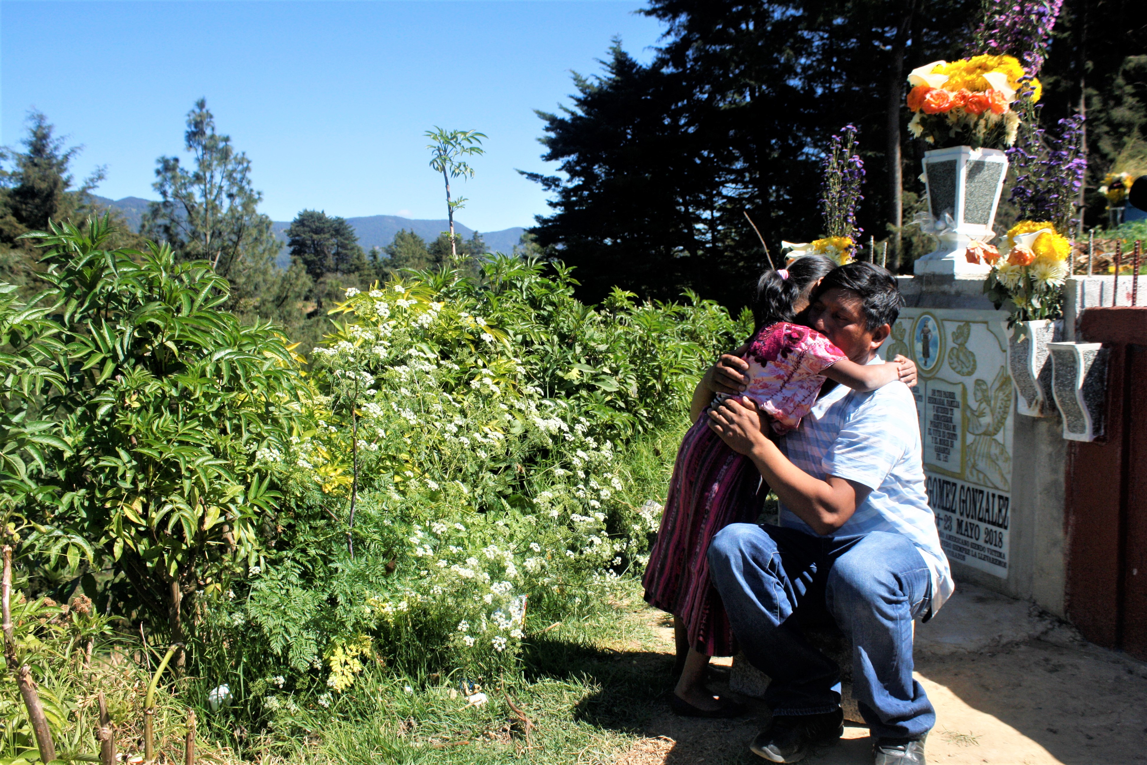 Gilberto Gomez-Gonzales hugs his youngest daughter during a visit to the cemetery where his eldest daughter, Claudia Gomez-Gonzalez, was laid to rest after she was killed by a U.S. Border Patrol agent in May and repatriated to her hometown of San Juan, Quetzaltenango, Guatemala. Image by Kristian Hernandez. Guatemala, 2018. Gilberto Gomez-Gonzales hugs his youngest daughter during a visit to the cemetery where his eldest daughter, Claudia Gomez-Gonzalez, was laid to rest after she was killed by a U.S. Border Patrol agent in May and repatriated to her hometown of San Juan, Quetzaltenango, Guatemala. Image by Kristian Hernandez. Guatemala, 2018.