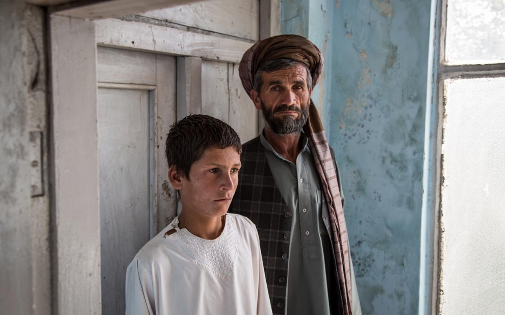 Nawroz and his son Zewarshah at their home in Charkh, Aghanistan, in 2015. Nawroz had sent his sons out to collect grain on the morning of August 3 only to have Zewarshah witness the death of his younger brother, Ayman, whose nickname was Sufi. Image by Jason Motlagh. Afghanistan, 2015.