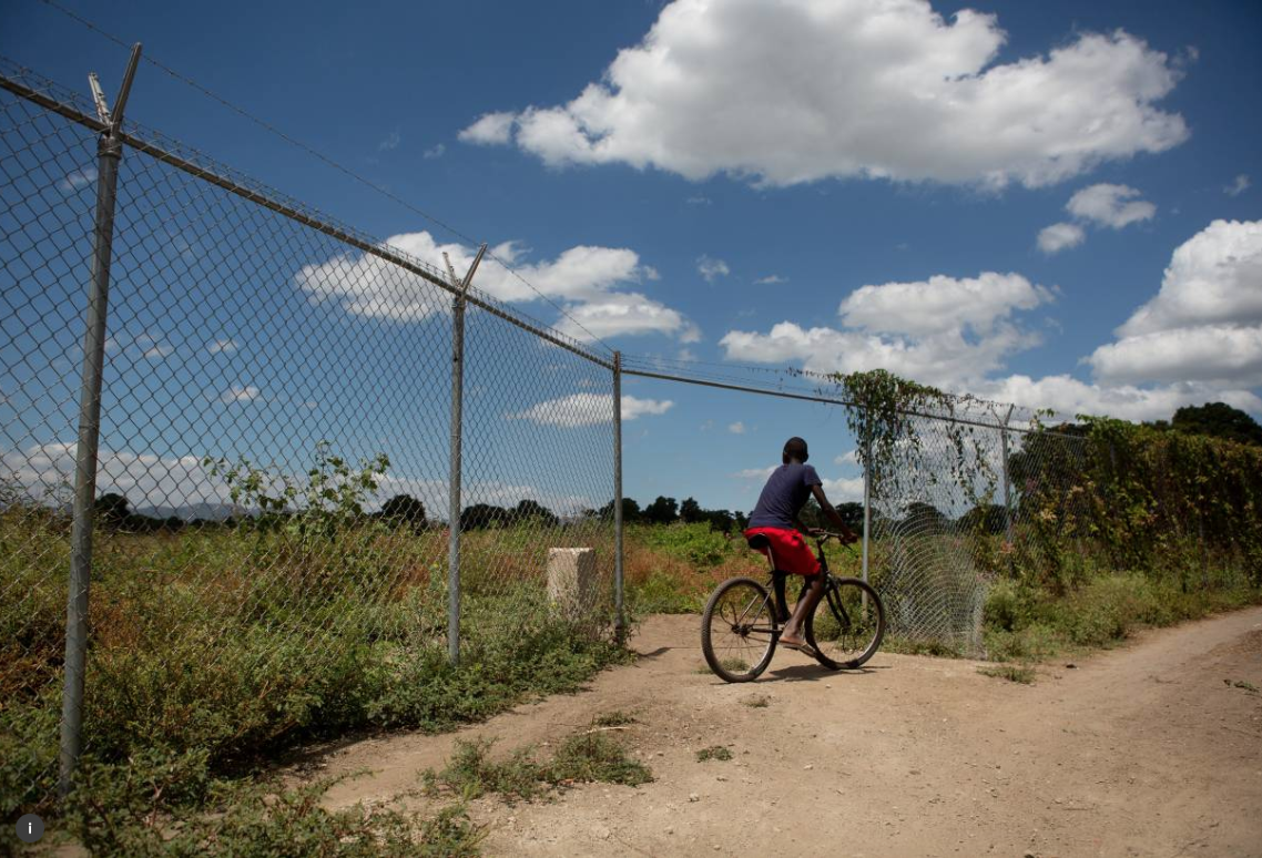A boy rides past fenced off land in the north of Haiti, April 14, 2015. Much of the area land was appropriated from local farmers to build the nearby Caracol Industrial Park. Image by Allison Shelley. Haiti, 2015. A boy rides past fenced off land in the north of Haiti, April 14, 2015. Much of the area land was appropriated from local farmers to build the nearby Caracol Industrial Park. Image by Allison Shelley. Haiti, 2015.