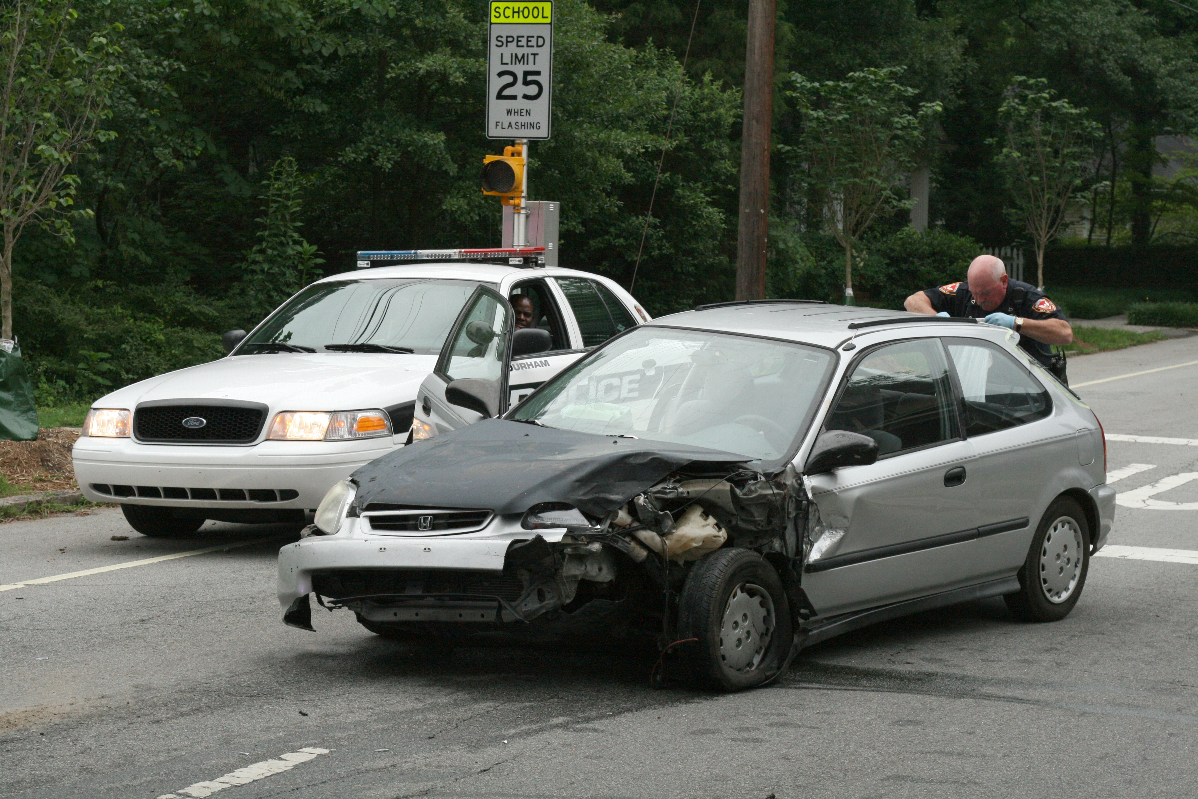 Police checking a car accident in Durham, N.C. Image by Ildar Sagdejev/Wikimedia Commons. United States, 2010. Media file: 2010-05-30_durham_police_checking_wrecked_honda_civic.jpg
