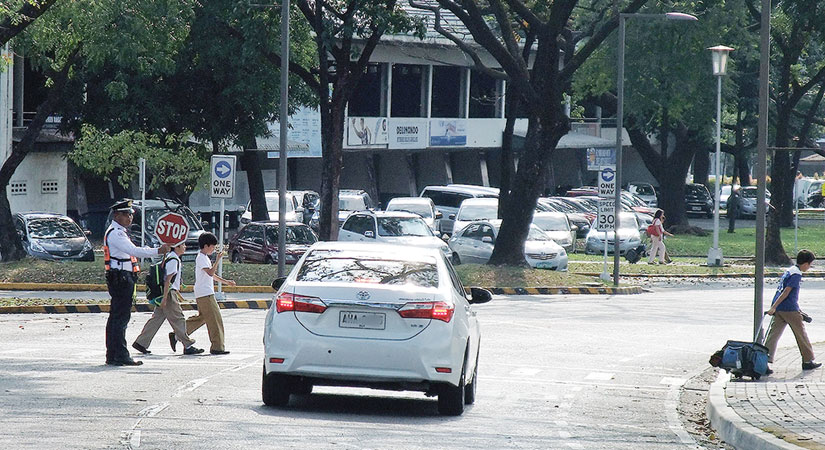 At the Ateneo de Manila University in Quezon City, security guards are trained to help students cross the street safely. Image by Dinna Louise C. Dayao. Philippines, 2019. At the Ateneo de Manila University in Quezon City, security guards are trained to help students cross the street safely. Image by Dinna Louise C. Dayao. Philippines, 2019.