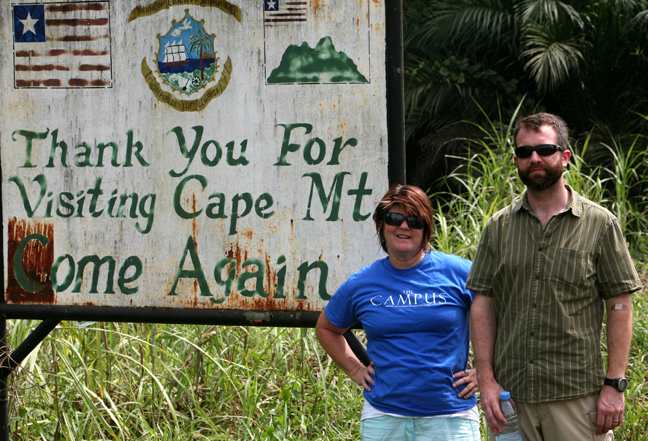 Photojournalist Cheryl Hatch and writer Brian Castner pose for a photograph as they leave Grand Cape Mount county in Liberia on Thursday, Jan. 15, 2015. Hatch is also the adviser to the student newspaper, The Campus, at Allegheny College, and she promised the students she'd take a photo with the shirt somewhere on her trip. Image by Prince Collins. Liberia, 2015. Media file: grandcapemount_9247.jpg