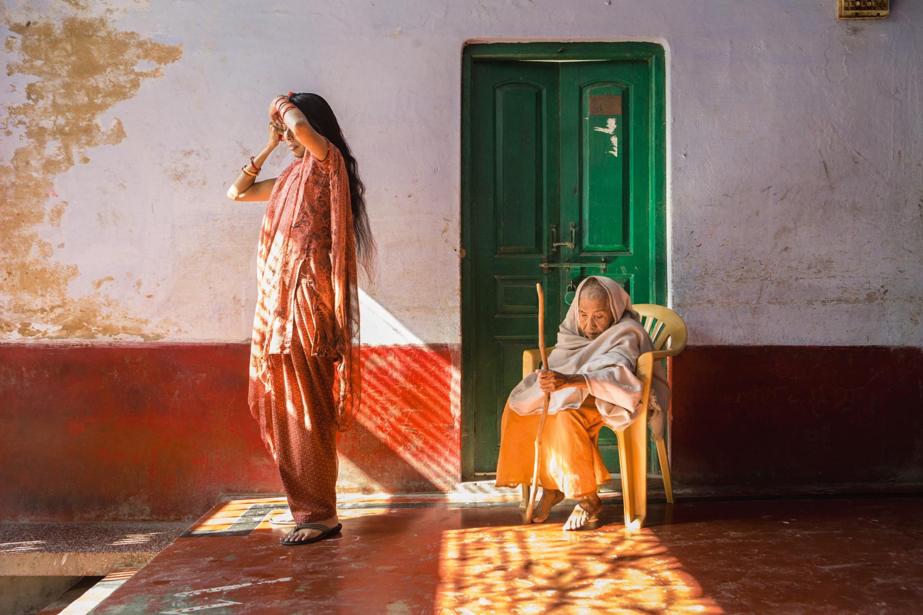 In a shelter in Vrindavan, known as a “city of widows,” Lalita (at right) bears the cropped hair and white wrap her culture once considered obligatory for widowhood. Shelter manager Ranjana, a much younger widow, is less constrained by traditional customs. Image by Amy Toensing. India, 2016. Media file: widows.jpg
