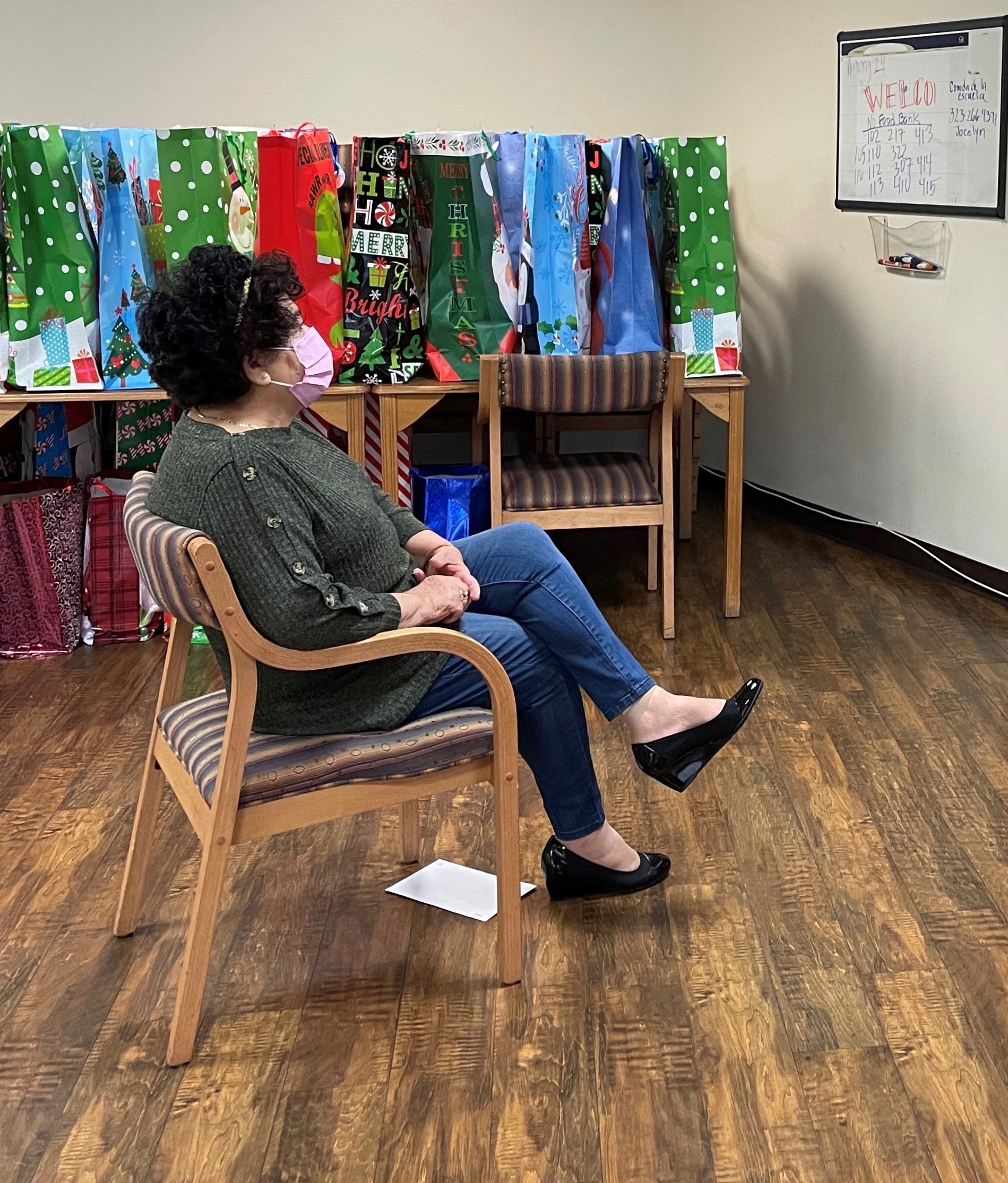 Mirna Cortez participates in a Zoom call in her building's community room, surrounded by holiday donations for seniors at the Retirement Housing Foundation. Image courtesy of Michelle Ornelas. United States, 2020. Mirna Cortez participates in a Zoom call in her building's community room, surrounded by holiday donations for seniors at the Retirement Housing Foundation. Image courtesy of Michelle Ornelas. United States, 2020.