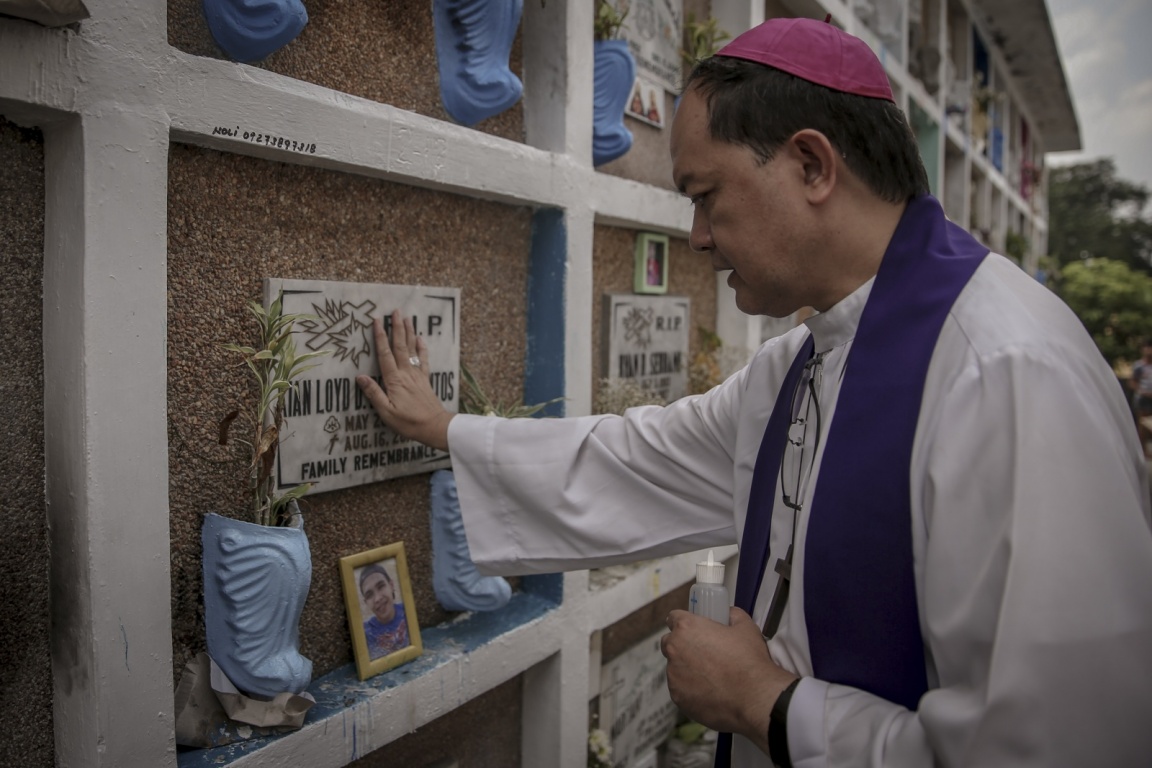 Bishop Pablo "Ambo" David prays over the tomb of Kian Loyd Delos Santos in La Loma Cemetary, Caloocan, Manila. Image by Eloisa Lopez. Philippines, 2018. Bishop Pablo "Ambo" David prays over the tomb of Kian Loyd Delos Santos in La Loma Cemetary, Caloocan, Manila. Image by Eloisa Lopez. Philippines, 2018.