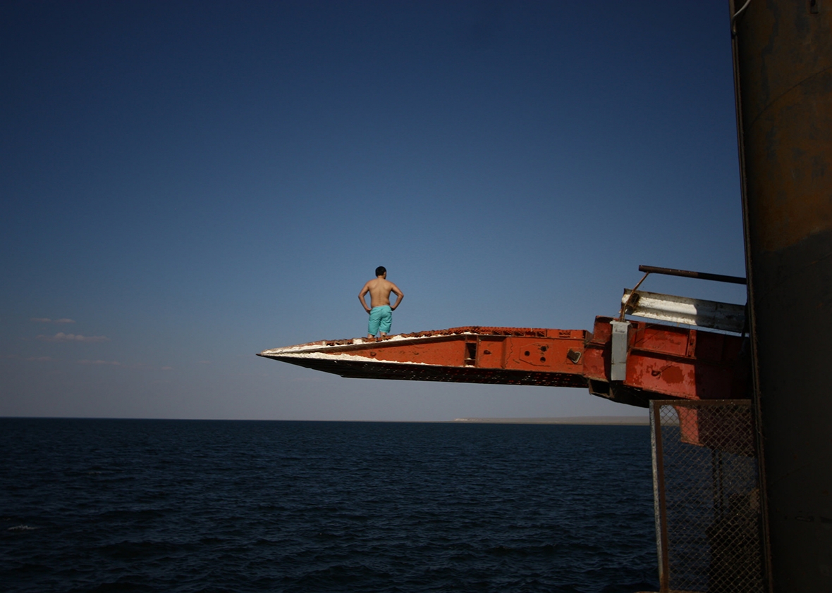 A man prepares to dive off a pier into the Caspian Sea in Sarytas, Kazakhstan, next to the spot where Russian geographers have determined is the true Europe–Asia border. Image by Joshua Kucera. Kazakhstan, 2016. A man prepares to dive off a pier into the Caspian Sea in Sarytas, Kazakhstan, next to the spot where Russian geographers have determined is the true Europe–Asia border. Image by Joshua Kucera. Kazakhstan, 2016.