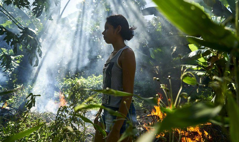 Joane beside a bonfire used to burn plastic waste. Image by Pablo Albarenga. Brazil, 2019. Joane beside a bonfire used to burn plastic waste. Image by Pablo Albarenga. Brazil, 2019.