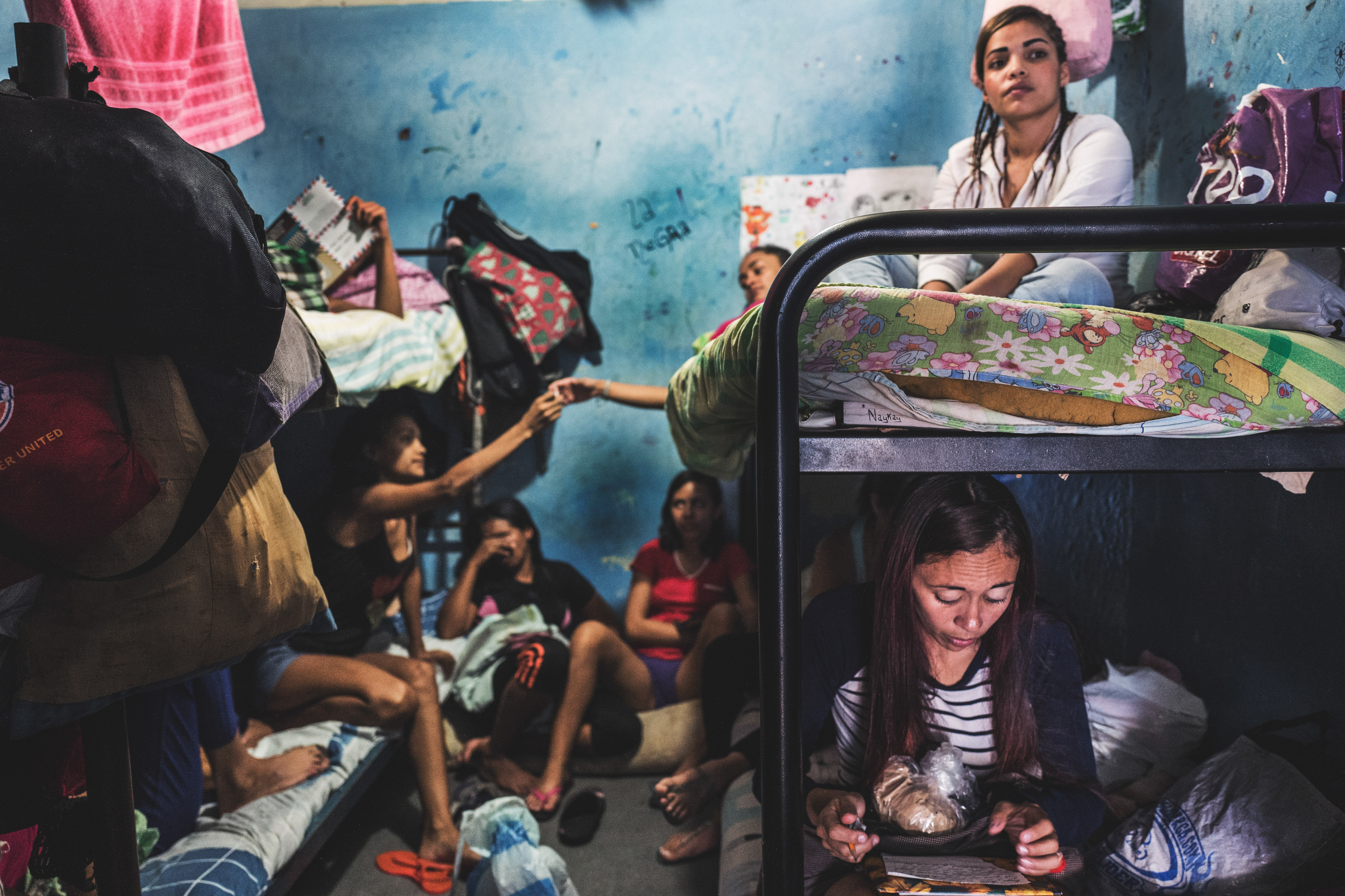 LA YAGUARA CENTER OF DETENTION, CARACAS - March 2018. Women inside a preventive detention center spend their days in a deranged inactivity. They adapte their space of their “dungeon” to make it look more like a home. They write letters or make drawings to their children, read the Bible, share cigarettes or iron their hair. Image by Ana María Arévalo. Venezuela, 2018. LA YAGUARA CENTER OF DETENTION, CARACAS - March 2018. Women inside a preventive detention center spend their days in a deranged inactivity. They adapte their space of their “dungeon” to make it look more like a home. They write letters or make drawings to their children, read the Bible, share cigarettes or iron their hair. Image by Ana María Arévalo. Venezuela, 2018.
