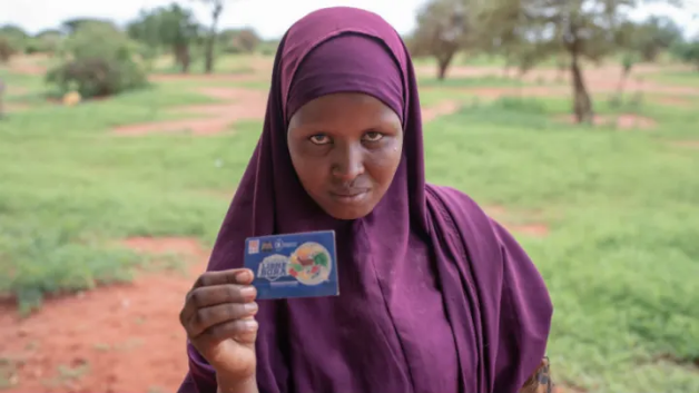 Farhiya Shimay Garore, 24, in Boji-Yeri, Wajir County. A resident of Boji-Yeri, she was registered into the World Food Programme project that targeted malnourished mothers and children under five. She was to receive cash transfers amounting to $120 over a period of three months. By the time the period ended she had only received $40. Image by Peter DiCampo. Kenya, 2019. Farhiya Shimay Garore, 24, in Boji-Yeri, Wajir County. A resident of Boji-Yeri, she was registered into the World Food Programme project that targeted malnourished mothers and children under five. She was to receive cash transfers amounting to $120 over a period of three months. By the time the period ended she had only received $40. Image by Peter DiCampo. Kenya, 2019.