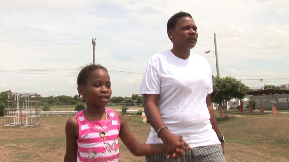 Simone Edwards walking with her daughter Khayla. Edwards, one of the characters in "The Abominable Crime" documentary, was attacked and shot in Jamaica because she is a lesbian. Image by Common Good Productions. Jamaica, 2013. Media file: simone_khayla.jpg