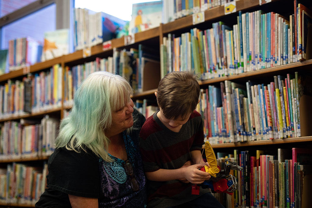 Anna Koski spends time with her grandson Aiden at the Miami Public Library. Aiden is the son of Koski’s younger daughter Jennifer. She hasn’t seen Elizabeth’s kids for several years. Image by Destiny Green / KOSU & The Frontier. United States, 2020. Anna Koski spends time with her grandson Aiden at the Miami Public Library. Aiden is the son of Koski’s younger daughter Jennifer. She hasn’t seen Elizabeth’s kids for several years. Image by Destiny Green / KOSU & The Frontier. United States, 2020.