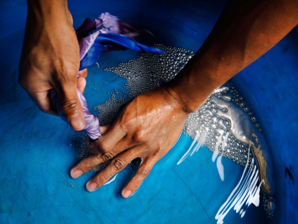 A young miner tends a ball mill beneath a Diwalwal home. Mercury in the blue pan is used during the process. Image by Larry C. Price. Philippines, 2013. Media file: price_diwalwal_edit_020.jpg