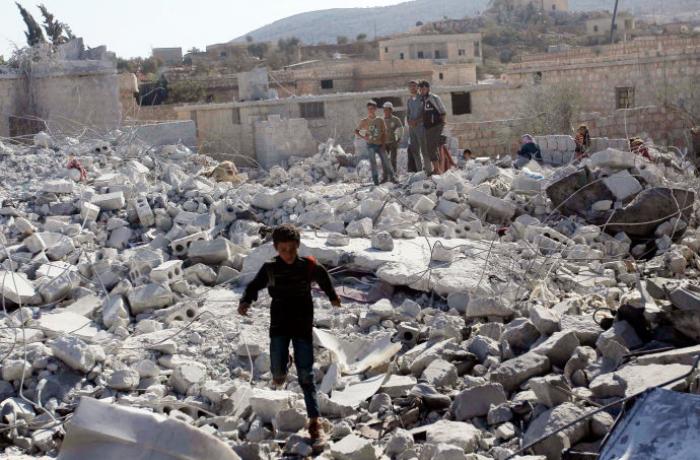 A boy plays in the ruins of a building destroyed by an airstrike. The deliberate destruction of antiquities by ISIS and others in Syria is considered a cultural genocide. Image courtesy of Peter Stevens flickr. Syria, 2014. Media file: harkins.jpg