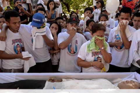 Family and friends of Alvin John Mendoza mourn as they spend their last moments with him on the day of his funeral on October 23, 2016. Mendoza, 23, was killed by unidentified riding-in-tandem gunmen while he was eating in a canteen near his home. Image by Eloisa Lopez. Philippines, 2016. A family and friends of the deceased grieve standing before an open casket.