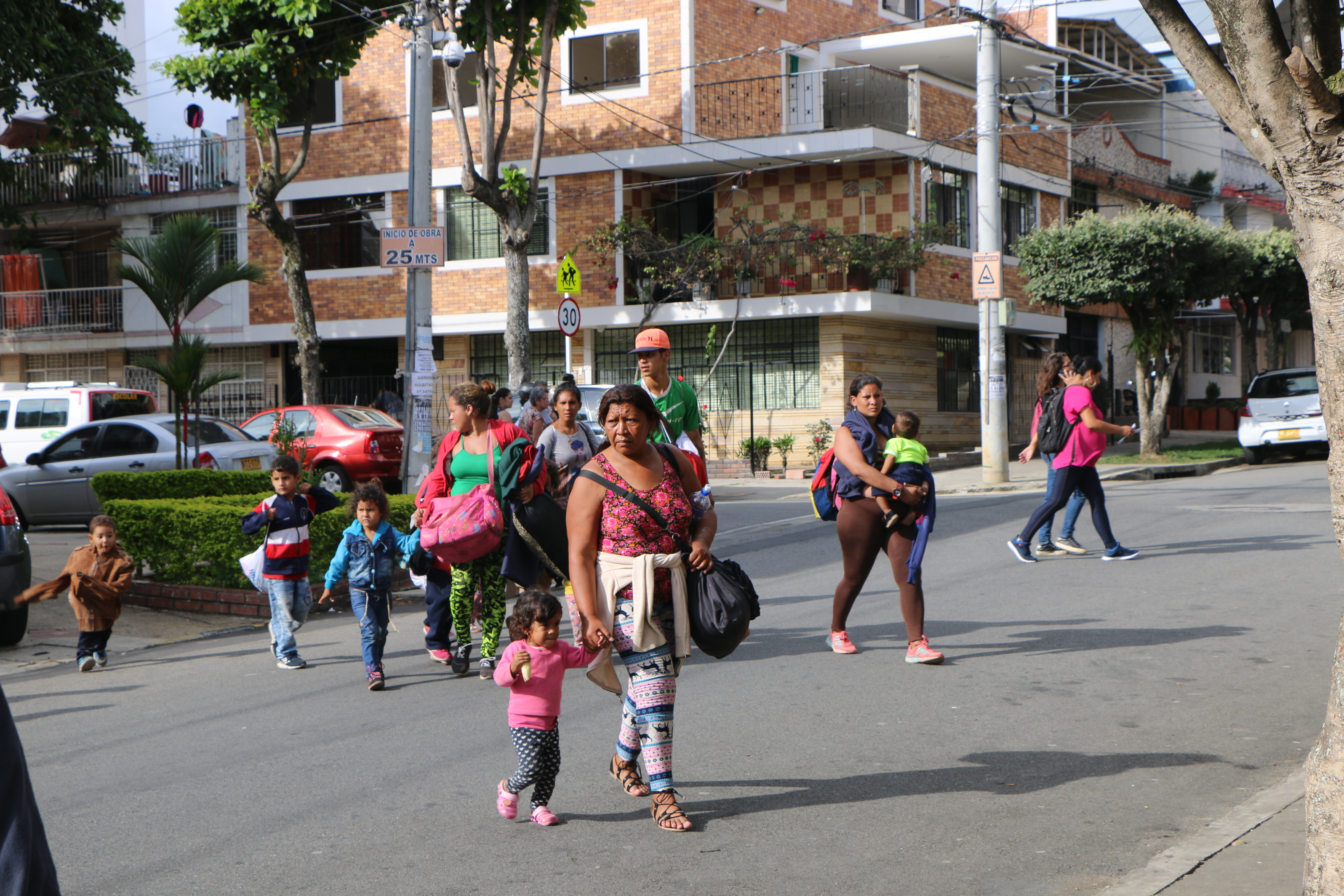 Venezuelan parents and children arrive at Fundación entre dos Tierras, one of the organizations providing aid to arriving migrants, in Bucaramanga, Colombia. At Fundación entre dos Tierras, volunteers serve migrants hot food and provide donations of clothing and other supplies. Image by Patrick Ammerman. Colombia, 2019. Venezuelan parents and children arrive at Fundación entre dos Tierras, one of the organizations providing aid to arriving migrants, in Bucaramanga, Colombia. At Fundación entre dos Tierras, volunteers serve migrants hot food and provide donations of clothing and other supplies. Image by Patrick Ammerman. Colombia, 2019.