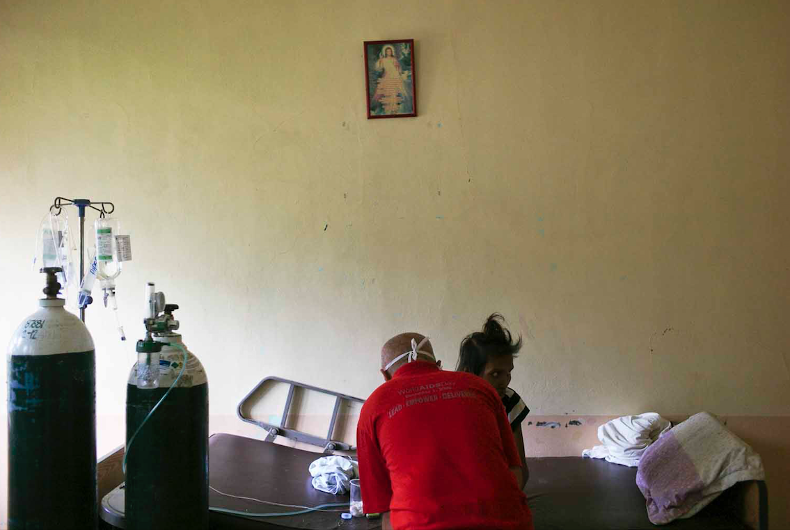 Brother Paul Bongcaras tends to Lilibeth, a 28-year-old woman suffering from opportunistic infections due to HIV. She was in that state when she went to see doctor who sent her home saying that it was “nothing serious.” She begged friends to find Brother Paul, knowing he was the only one who could help her. Image by Veejay Villafranca. Philippines, 2015.