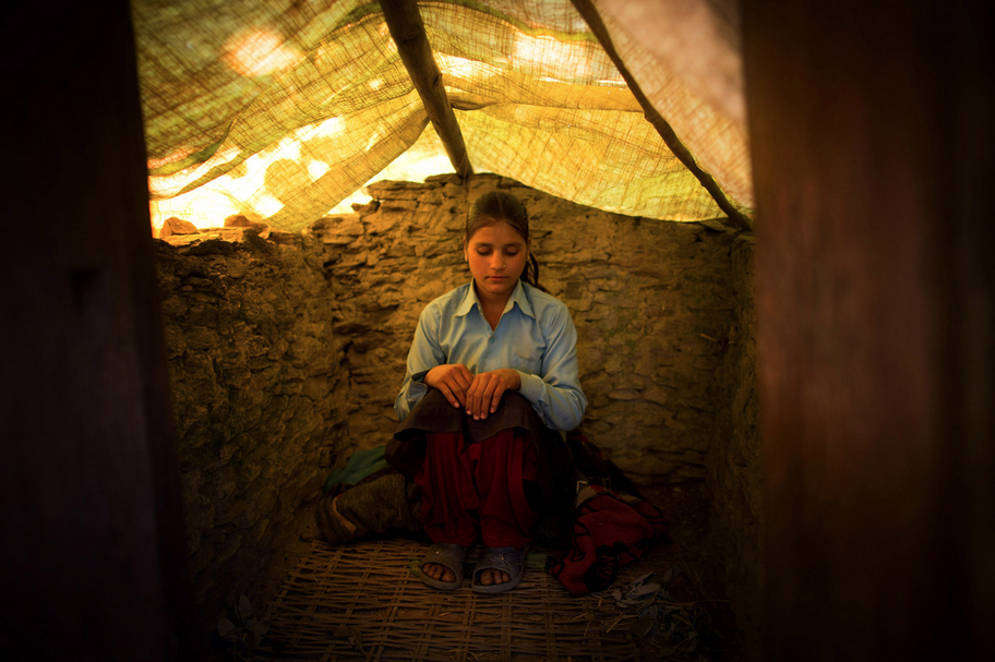 Jaukala, 14, poses for a photo in the family's chaupadi shelter, a squat shed measuring approximately 1 meter by 2 meters, in Rima village, Achham, Nepal. A tarp serves as a temporary roof to this structure, still under construction. Jaukala must sleep here while she has her period. Image by Allison Shelley. Nepal, 2012. Media file: Screen Shot 2013-02-28 at 2.36.09 PM.png