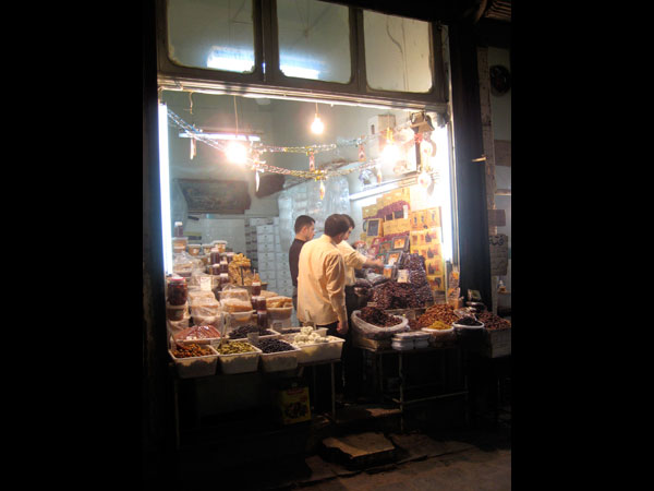 A purveyor of olives, dates, fresh cheese, and honey in the Aleppo souq. A mild climate, cosmopolitan history, and lots of French tourists conspire to make Aleppo's food some of the best in the Middle East. Media file: 02_Aleppo_Spice_Stall.jpg