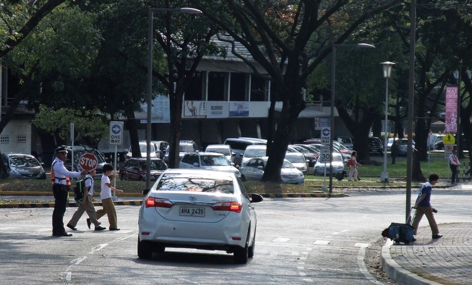 At the Ateneo de Manila University in Quezon City, security guards are trained to help students cross the street safely. Image by Dinna Louise C. Dayao. Philippines, 2019. At the Ateneo de Manila University in Quezon City, security guards are trained to help students cross the street safely. Image by Dinna Louise C. Dayao. Philippines, 2019.