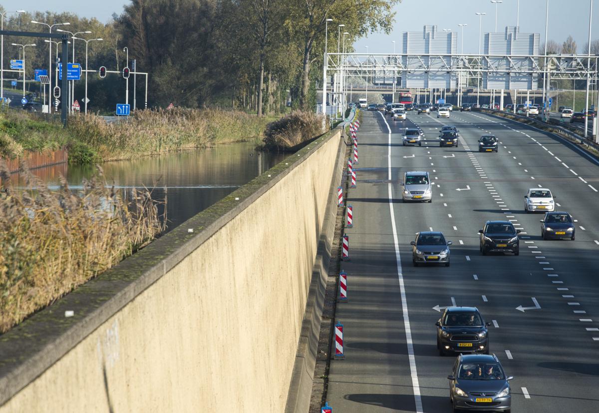 A large wall holds back water, left, as cars on an highway drive under an approaching canal near Rotterdam. Image by Chris Granger. Netherlands, 2019. A large wall holds back water, left, as cars on an highway drive under an approaching canal near Rotterdam. Image by Chris Granger. Netherlands, 2019.