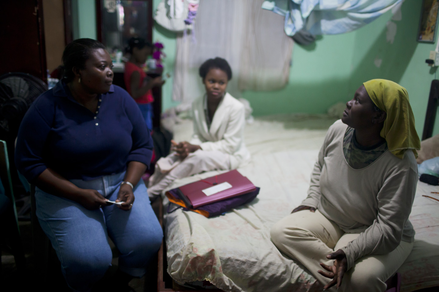 Carmen Suyapa (right) speaks with a local health worker as her daughter watches. Image by David Rochkind. Honduras, 2013. Media file: Rochkind_Garifuna019.jpg
