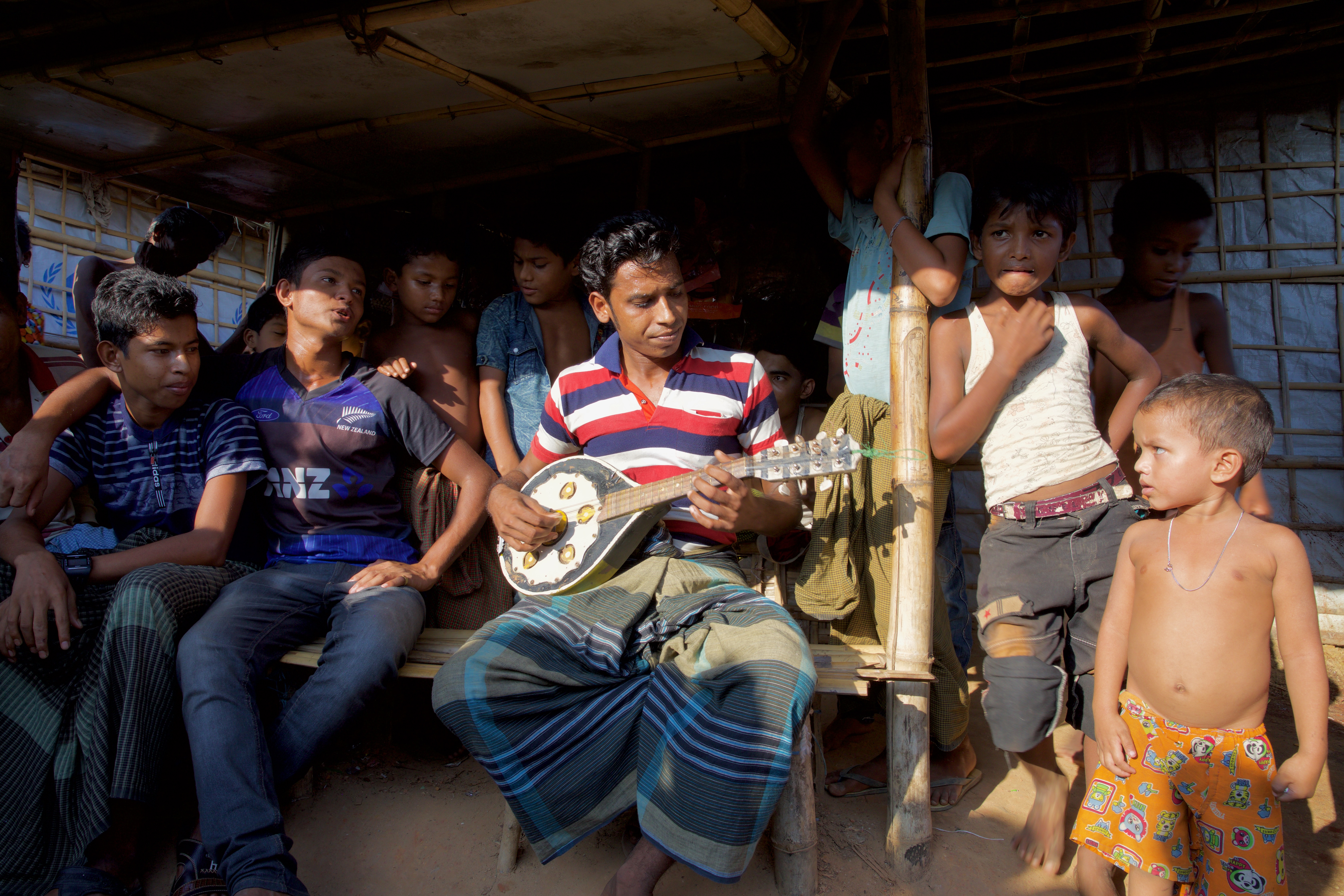 Image by Faiham Ebna Sharif. Bangladesh, 2019. Musician holding a mandolin, surrounded by listeners. Image by Faiham Ebna Sharif. Bangladesh, 2019.