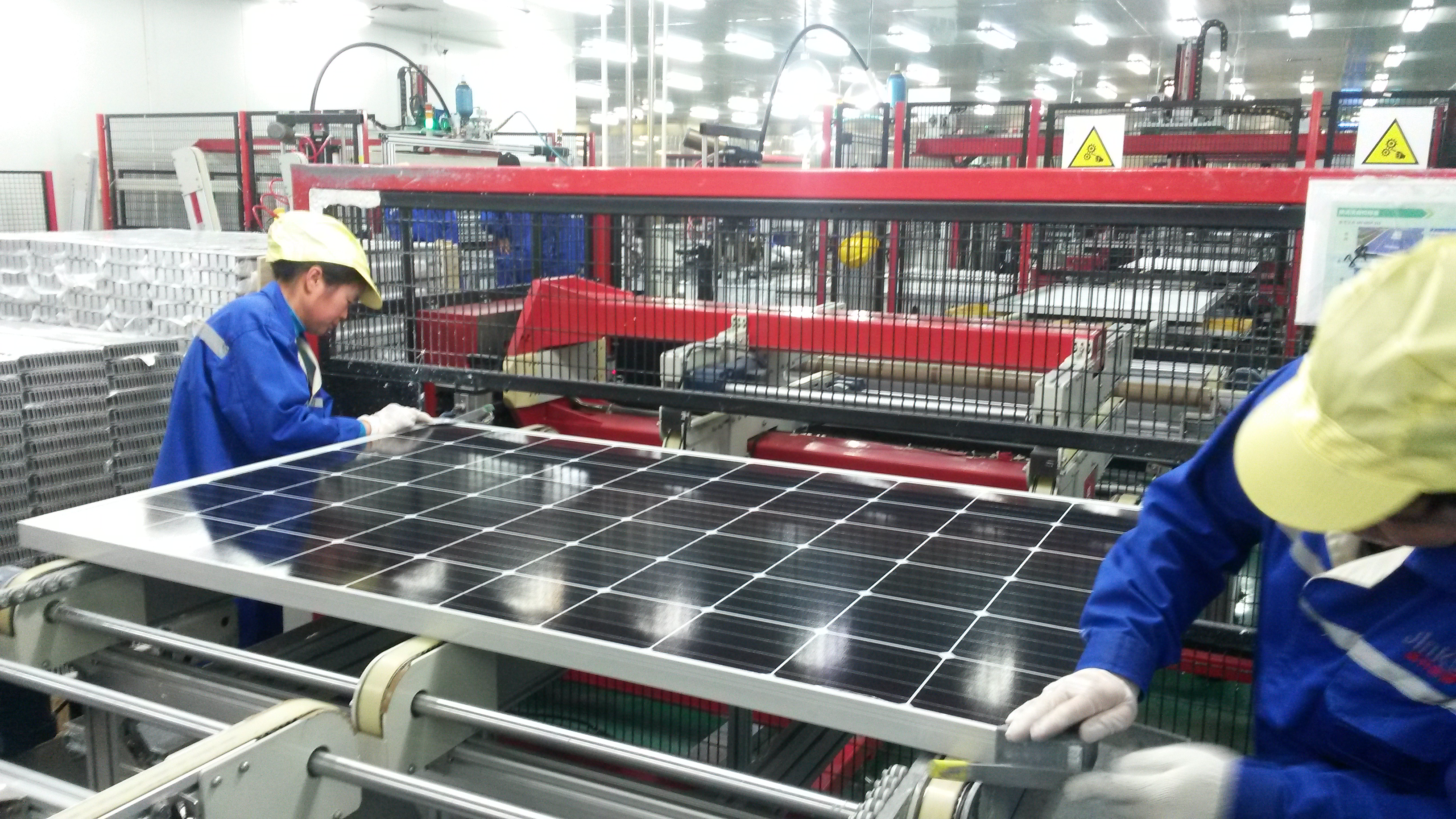 Workers assemble a solar panel at Jinko Solar’s factory in Haining, Zhejiang province. China is in the midst of the world’s biggest-ever investment in renewable power, seeking to reduce its reliance on coal and ease air pollution that is estimated to kill more than a million people in the country every year. Image by Beth Gardiner. China, 2017. Workers assemble a solar panel inside of a factory in Haining, Zhejiang province, China.