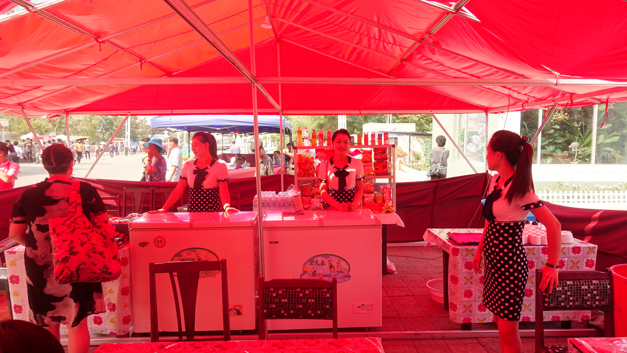Servers at a snack counter in a tent located outside a cinema in Pyongyang during the Pyongyang International Film Festival. Image by Laya Maheshwari. North Korea, 2016. Servers at a snack counter in a tent located outside a cinema in Pyongyang during the Pyongyang International Film Festival. Image by Laya Maheshwari. North Korea, 2016.