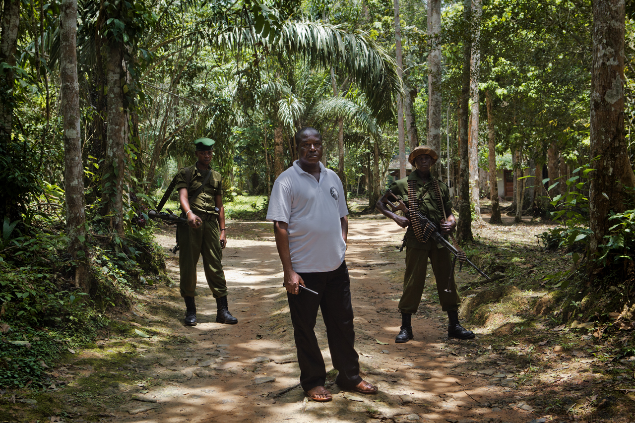 Bernard Iyomi Iyatshi, the new director of the Wildlife Authority in the Ituri rainforest, stands with two heavily armed park rangers at their base in Epulu, Mambasa territory. Image by Francesca Tosarelli. Province Orientale, DRC, 2013. Media file: _MG_2284.jpg