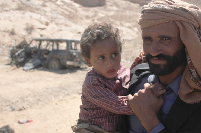 Mabkhout Ali al Ameri stands with his 18-month-old son, Mohammed, in the village of al Ghayil in Yemen’s al Bayda province. Mabkhout’s wife, Fatim Saleh Mohsen, was shot in the back of the head by helicopter gunship fire as she fled with Mohammed in her arms during a U.S. raid. Image courtesy of The Intercept. Yemen, 2017. Mabkhout Ali al Ameri stands with his 18-month-old son, Mohammed, in the village of al Ghayil in Yemen’s al Bayda province. Mabkhout’s wife, Fatim Saleh Mohsen, was shot in the back of the head by helicopter gunship fire as she fled with Mohammed in her arms during a U.S. raid. Image courtesy of The Intercept. Yemen, 2017.