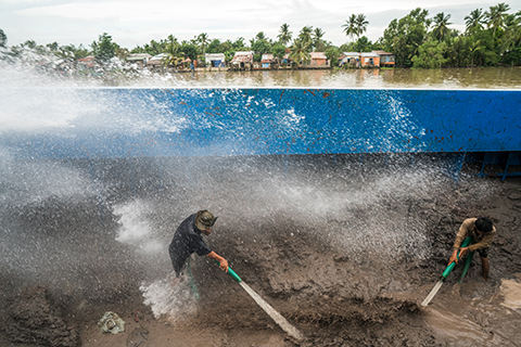 Sand barge workers near Can Tho City hose down a mountain of sand pumped up from branches of the Mekong. The wet sand is then pumped through underground pipes to a road construction site further inland. Sand barge workers near Can Tho City hose down a mountain of sand pumped up from branches of the Mekong. The wet sand is then pumped through underground pipes to a road construction site further inland.
