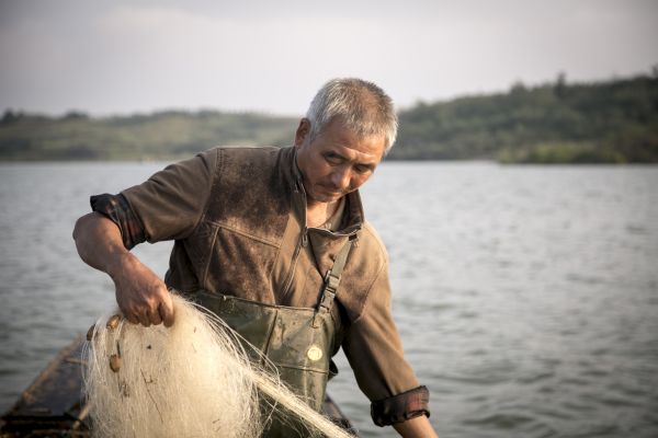 During the course of the year that Sharron Lovell filmed him, fisherman Cao Suizhou’s hair turned from jet black to white, a sign of stress for a man who otherwise endures his worries in silence. When asked what he wants people to know about China’s radical remedy to its water crisis, he said, “Just to understand what we’ve gone though, we know we can’t fight it or change anything, but people in Beijing should know where their water is coming from.” Image by Tom Wang. China, 2015.