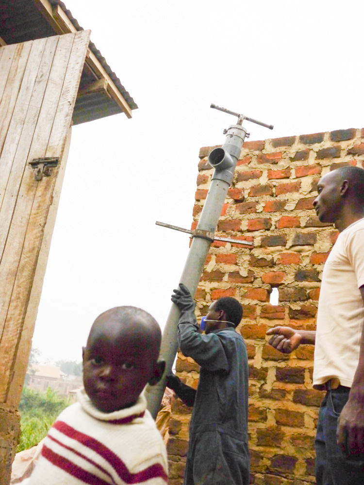 David Asiimwe, age 2, watches as John Businge and his "Gulper" team empty out his family's toilet - they've been waiting for six weeks. Image by Sam Loewenberg. Uganda, 2014. Media file: p1040088.jpg