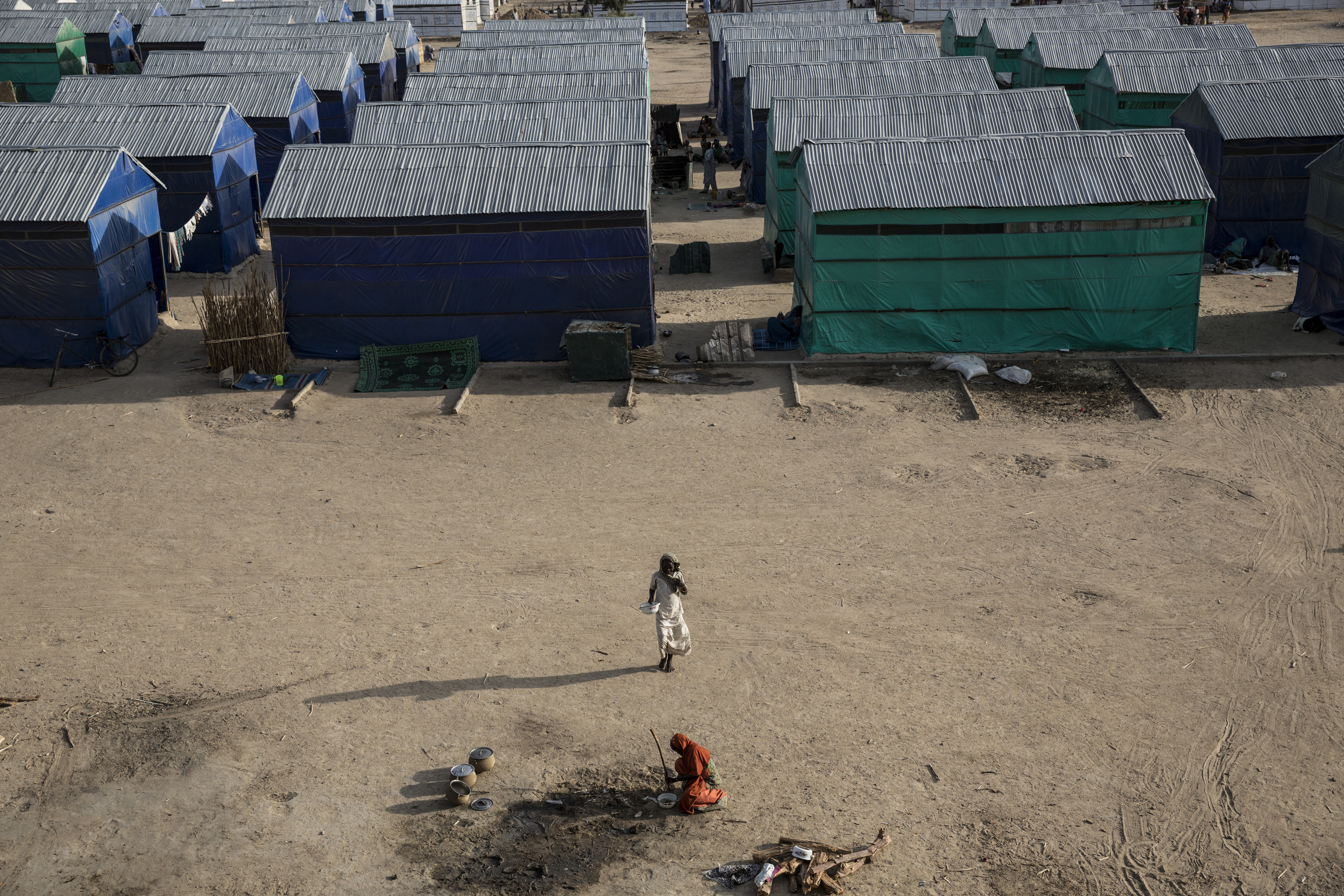 A young woman walks through Custom House, a large IDP camp on the outskirts of Maiduguri that is home to over 9,000 people. There are more than 1.7 million displaced in Northern Nigeria alone, and the number of shelters at refugee camps does not meet the needs of the huge population. The camps that do exist are often cut off from town and markets and frequent sites of suicide bombs. Image by Sarah A. Topol. Nigeria, 2017. A young woman walks through Custom House, a large IDP camp on the outskirts of Maiduguri that is home to over 9,000 people. There are more than 1.7 million displaced in Northern Nigeria alone, and the number of shelters at refugee camps does not meet the needs of the huge population. The camps that do exist are often cut off from town and markets and frequent sites of suicide bombs. Image by Sarah A. Topol. Nigeria, 2017.