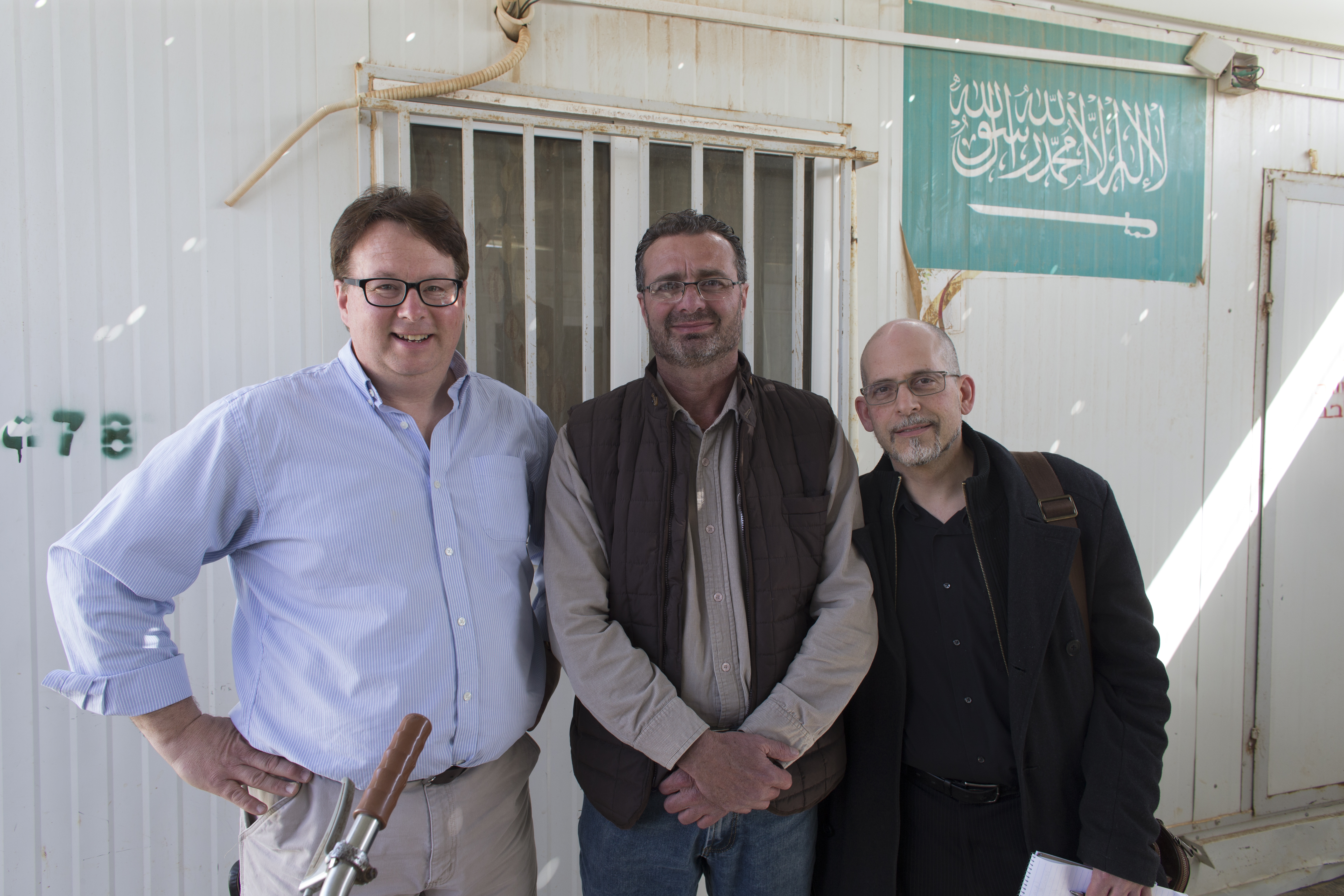 Ihab Muhtaseb (center) is shown with Milwaukee Journal Sentinel staffers Mark Hoffman (left) and Mark Johnson Wednesday, March 22, 2016 at the Zaatari refugee camp in Jordan about 15 miles from the Syrian border. Muhtaseb was an interpreter for the pair. Image by Mark Hoffman. Jordan, 2016. Media file: jordan_day_five_blog.jpg