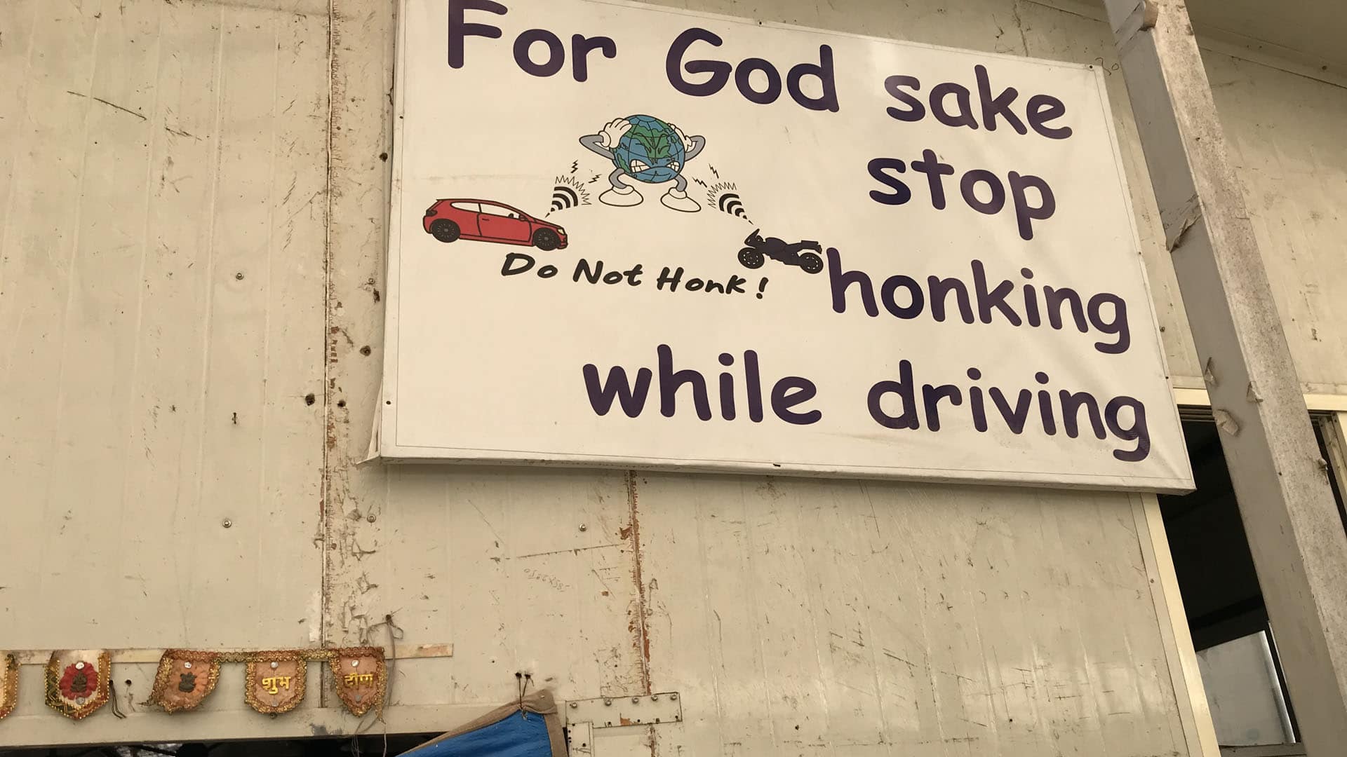 An anti-honking sign hangs on the wall at the Earth Saviours Foundation just outside New Delhi. The foundation is active in caring for the homeless and several environmental causes, including noise pollution. Image by Chris Berdik. India, undated. An anti-honking sign hangs on the wall at the Earth Saviours Foundation just outside New Delhi. The foundation is active in caring for the homeless and several environmental causes, including noise pollution. Image by Chris Berdik. India, undated.