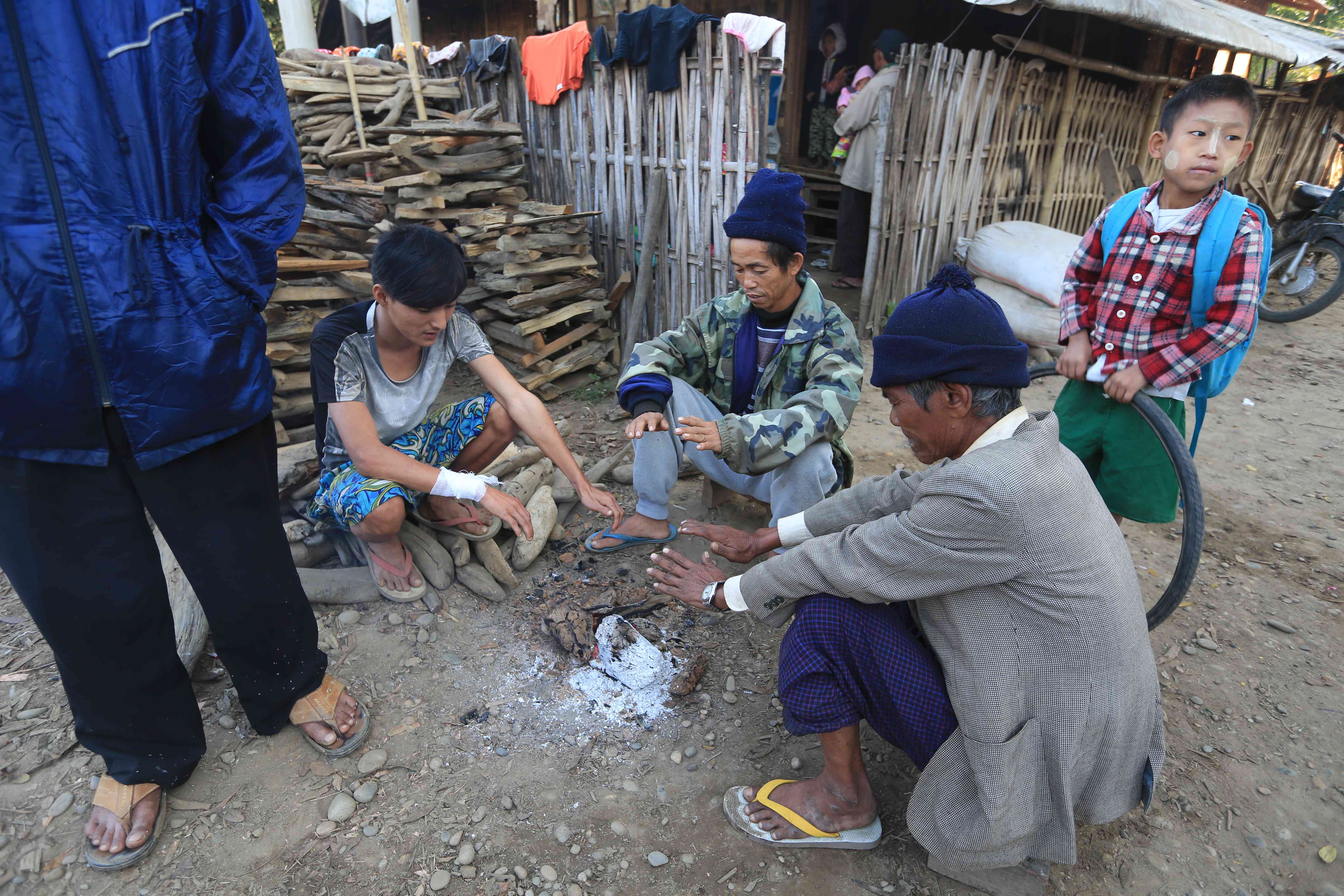 Ethnic Kachin villagers uprooted from their homes by nearby fighting warm themselves by a fire at a displaced persons camp in Myitkyina, Burma. Image by Jason Motlagh.